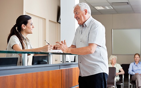 Older man checking in at dental office reception desk