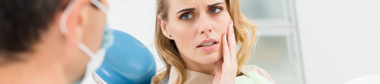 Woman in dental chair holding cheek