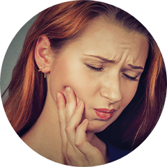 Woman with red hair holding her cheek in pain