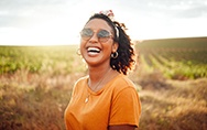 Smiling woman in orange shirt standing in a field