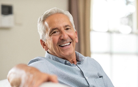 older man smiling while sitting on living room couch