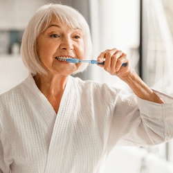 woman brushing teeth in bathroom mirror