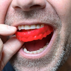 man putting mouthguard in mouth
