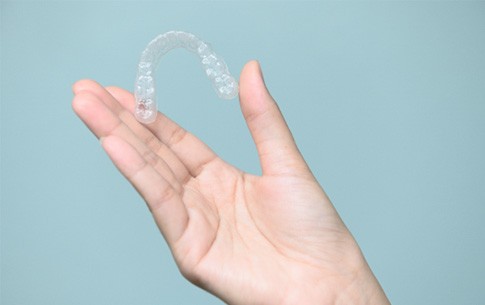 Patient holding Invisalign clear aligner