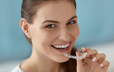 Smiling woman holding an Invisalign tray