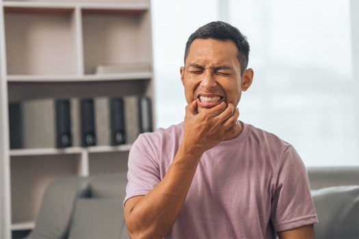 Man squinting in pain touching fingers to corners of lips