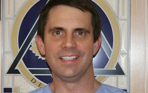 Dentist in front of dental award sign