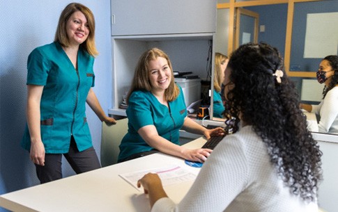 Dental assistants reviewing price of treatment with patient in office