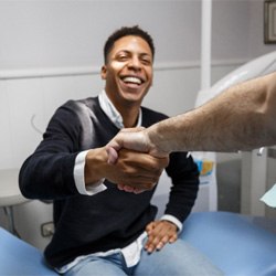 Dentist and patient shaking hands at consultation 