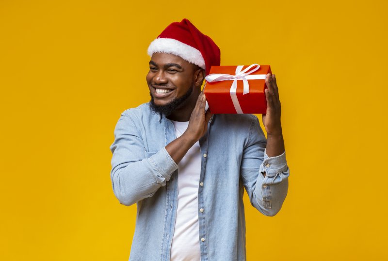 a man wearing a Santa hat and holding a present while smiling