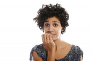 Concerned woman chewing her fingernails needs to see her dentist