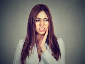 Pained woman with hand oat cheek needs to see her Conway emergency dentist