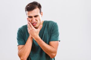 man holding face in pain due to dental emergency 