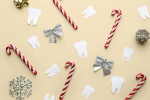 Decorative candy canes, snowflakes, ribbons, and paper teeth on a yellow background