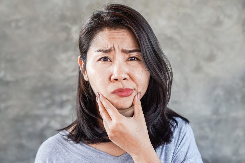 Patient rubbing their cheeks due to impacted wisdom teeth