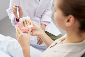 Patient holding a dental implant model while dentist points to it