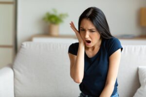 Woman holding jaw with surprised expression.