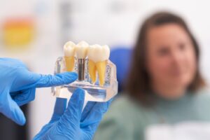 Dental implant being shown in foreground while patient looks on in background.